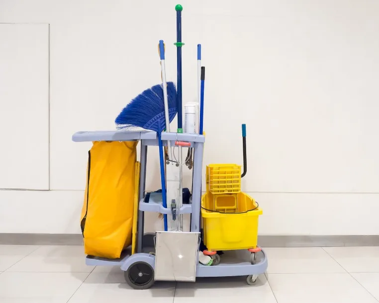 Carro de limpieza equipado con cubo de fregado, mopas, escobas y bolsa de residuos